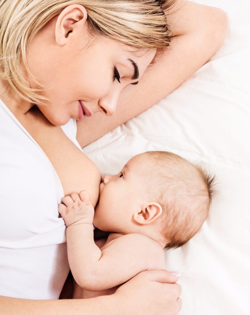 Imagen de una madre dando el pecho a su hijo en la cama.